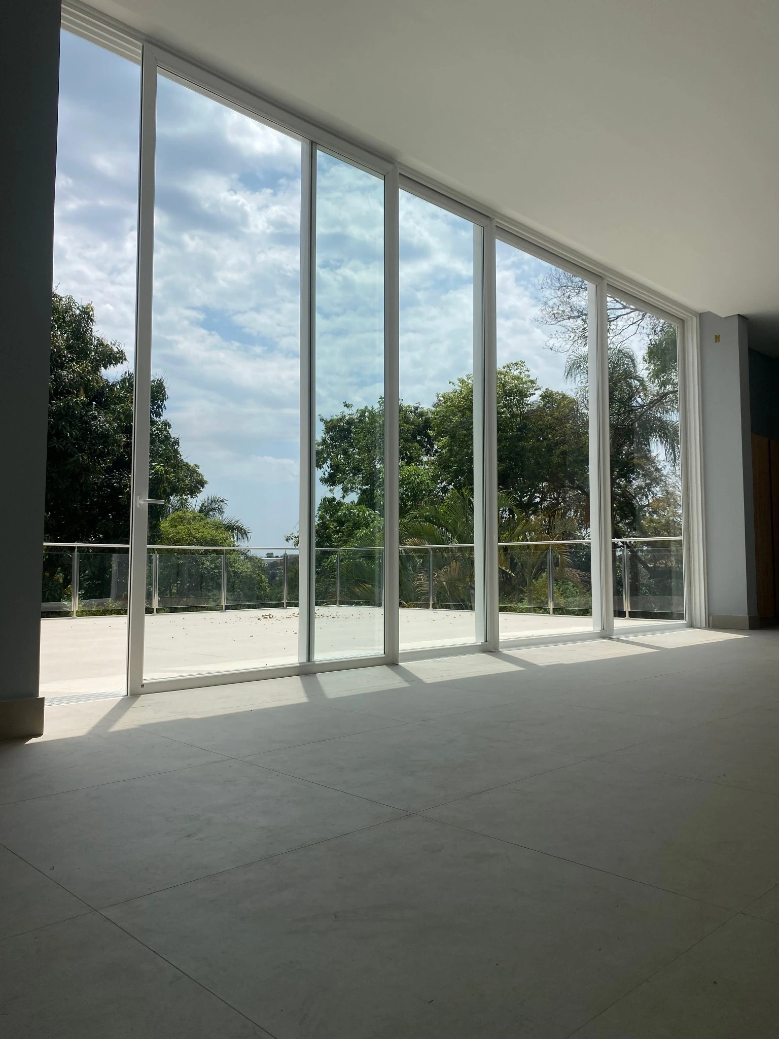 Porta de correr branca de quatro folhas com vista para a varanda e o jardim