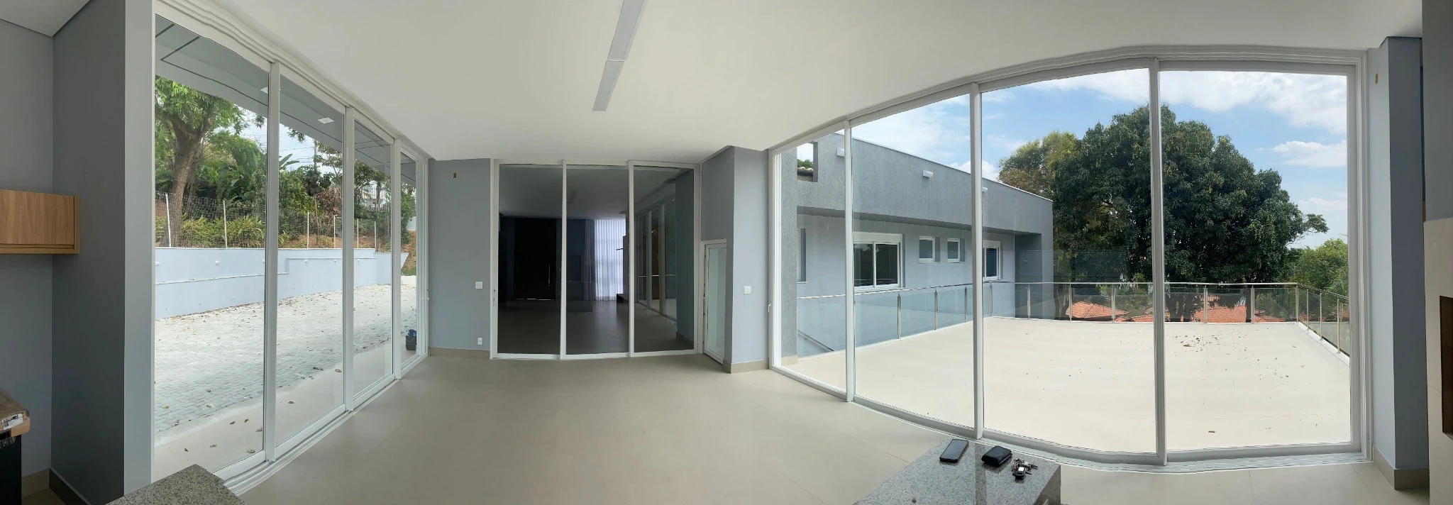 Esquadrias brancas de quatro folhas em uma ampla sala com vista para o terraço